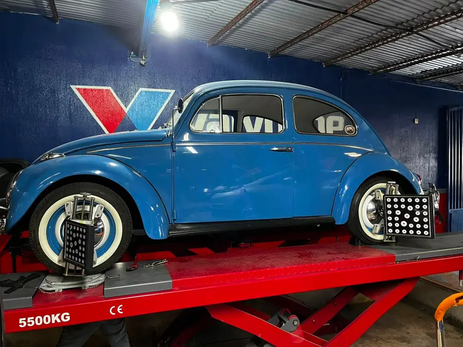 Volkswagen Escarabajo azul de perfil sobre el elevador de tijera del taller