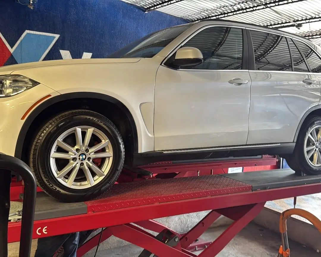 Camioneta SUV blanca sobre la rampa de alineación del taller