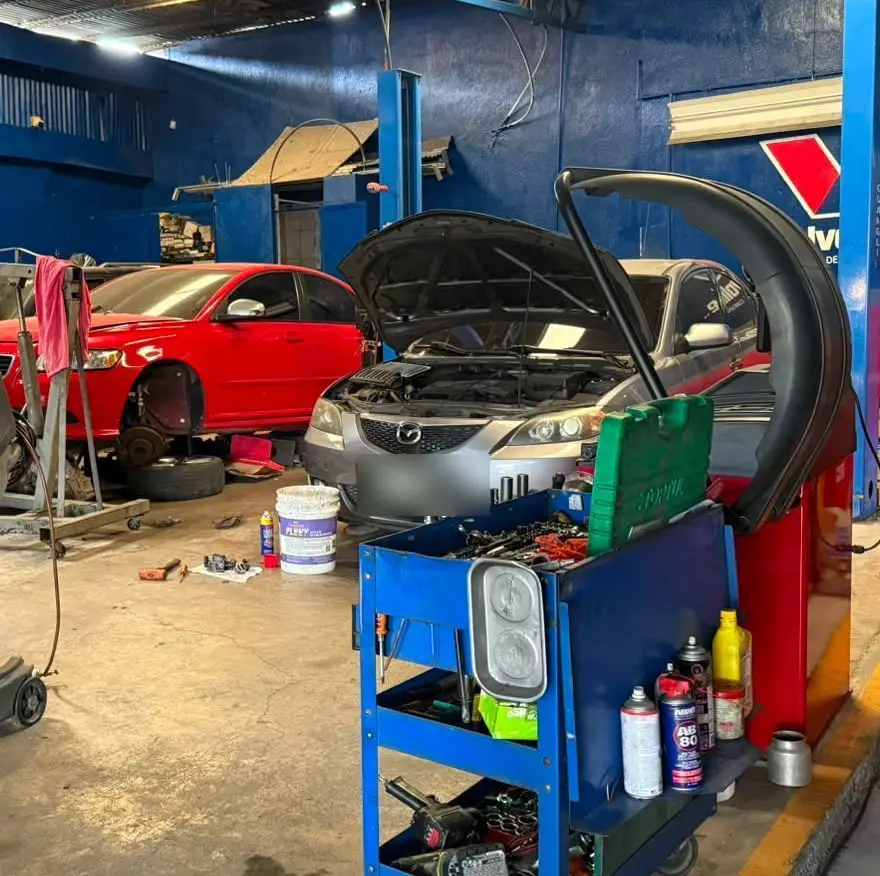 Vehículos con el capó abierto en servicio de aire acondicionado junto al carro de herramientas del taller