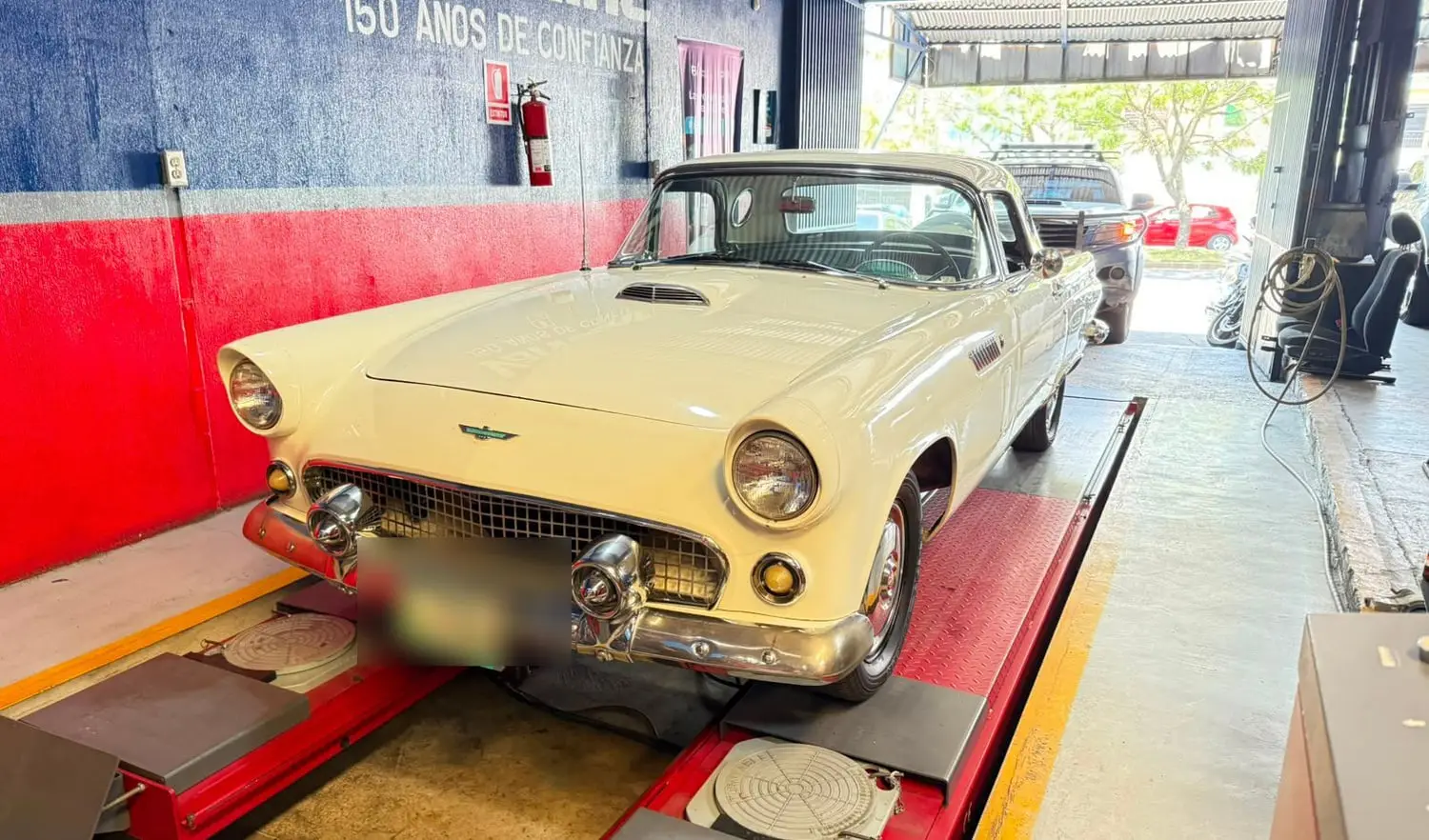 Automóvil clásico convertible estacionado en la bahía del taller junto al rótulo de Valvoline