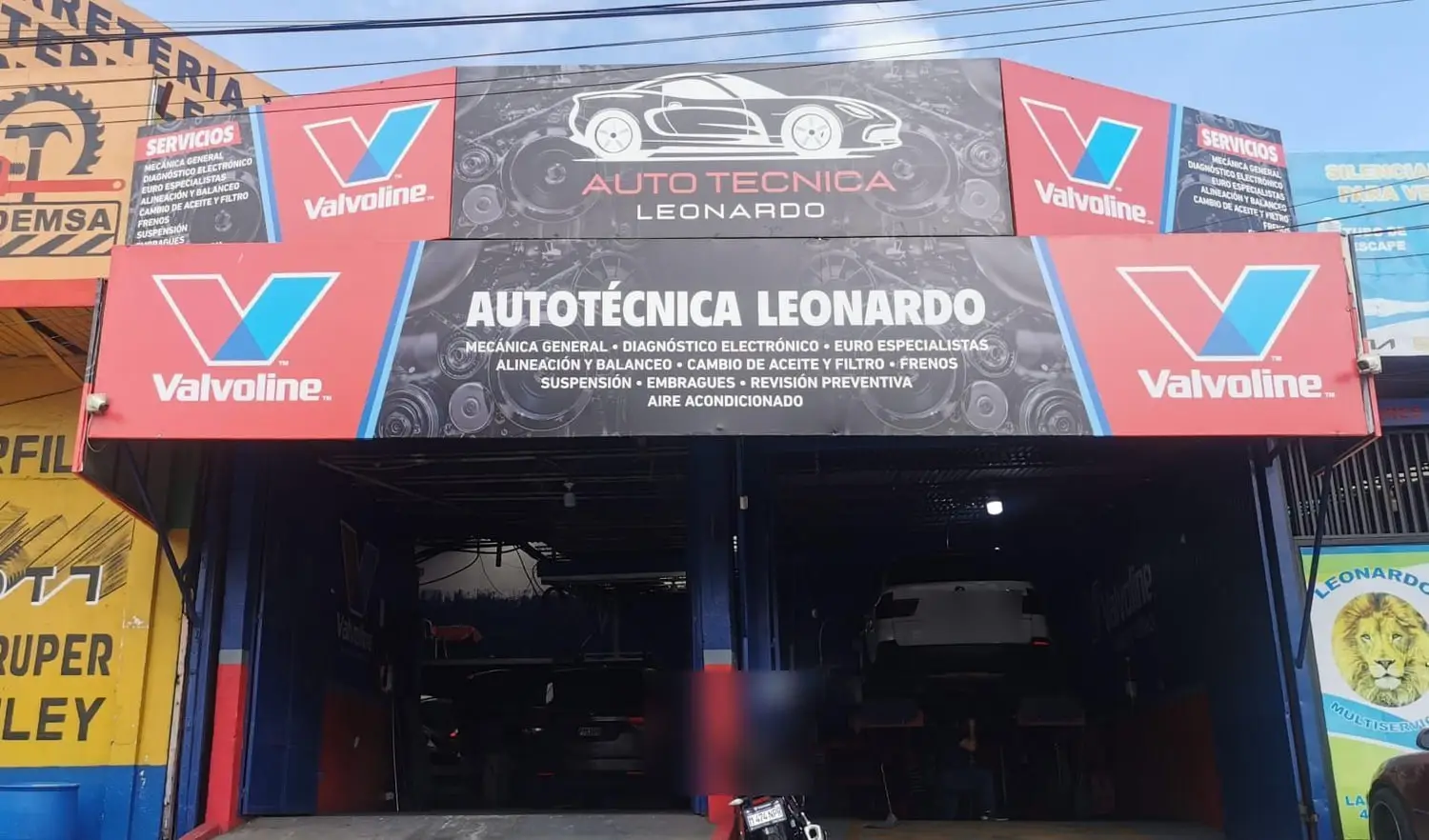 Fachada de Auto Técnica Leonardo con el rótulo de servicios y el anuncio Valvoline sobre la entrada