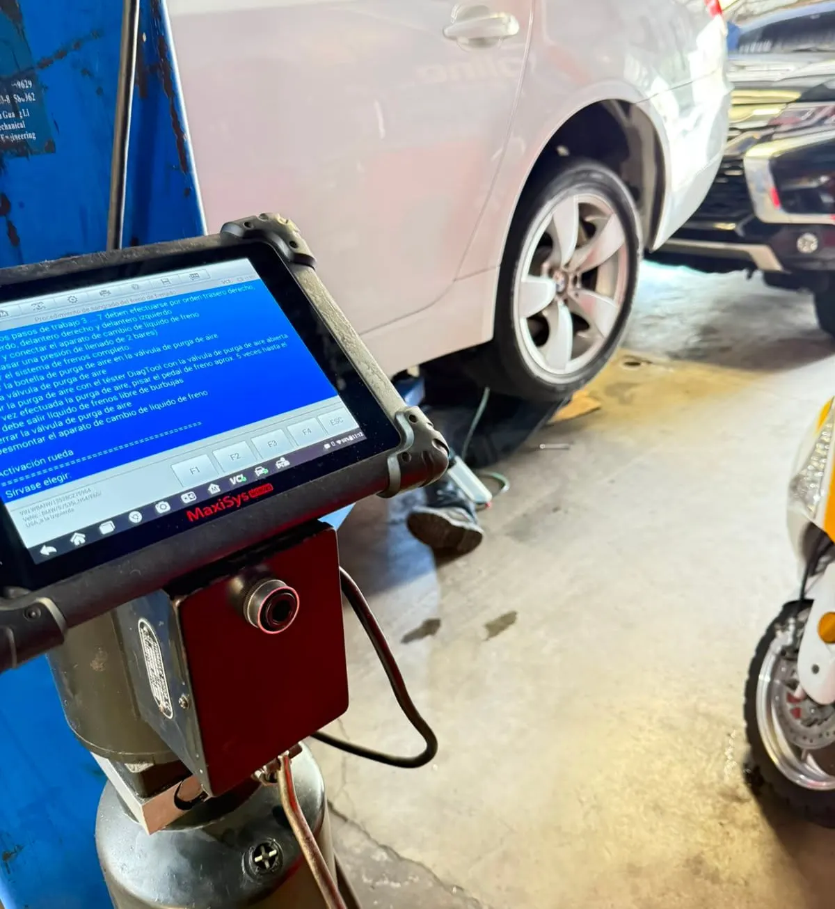 Técnico revisando el motor de un vehículo con lámpara de trabajo dentro del taller